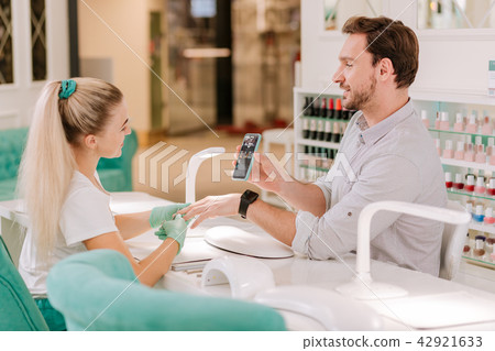 Dark-haired metrosexual showing some photos his nail master 42921633