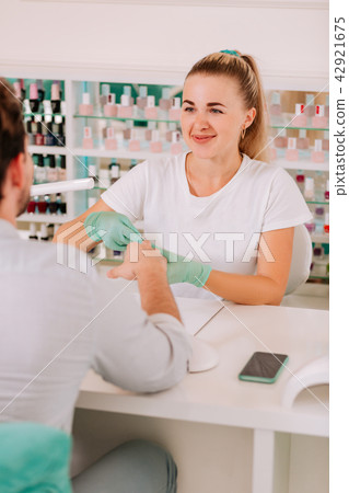 Pleasant professional nail master making manicure for man Pleasant professional nail master making manicure for man 42921675