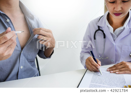 Doctor with a thermometer in his hand taking patient's in hospit 42921784