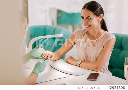 Dark-haired client of nail bar feeling satisfied with service Dark-haired client of nail bar feeling satisfied with service 42921808