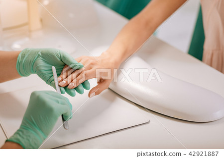 Client of beauty salon wearing beige blouse sitting having manicure Client of beauty salon wearing beige blouse sitting having manicure 42921887