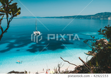 White catamaran yacht at anchor on clear azure water surface in calm blue lagoon. Unrecognizable White catamaran yacht at anchor on clear azure water surface in calm blue lagoon. Unrecognizable 42922153