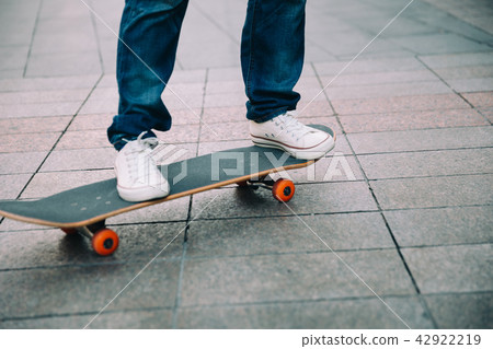 Skateboarder legs riding skateboard on city street Skateboarder legs riding skateboard on city street 42922219