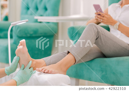 Woman wearing grey trousers sitting enjoying feet massage Woman wearing grey trousers sitting enjoying feet massage 42922310