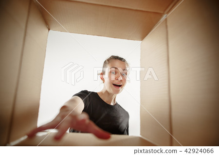 Woman unpacking and opening carton box and looking inside Woman unpacking and opening carton box and looking inside 42924066