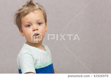 Sleepy disheveled cute baby looking at camera against grey background. Copy space. Sleepy disheveled cute baby looking at camera against grey background. Copy space. 42926979