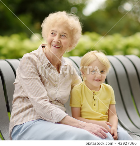 Beautiful granny and her little grandson walking together in park Beautiful granny and her little grandson walking together in park 42927366