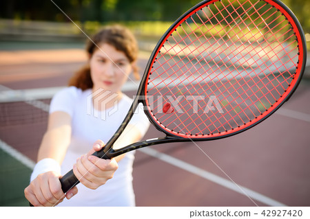 Young female tennis player with tennis racket preparing to serve Young female tennis player with tennis racket preparing to serve 42927420