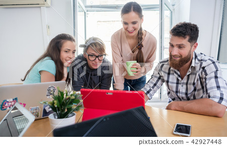 Four co-workers watching a business presentation in a modern shared office 42927448