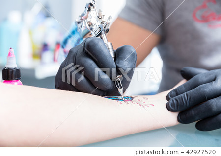 Close-up of the hands of a skilled tattoo artist wearing black gloves Close-up of the hands of a skilled tattoo artist wearing black gloves 42927520