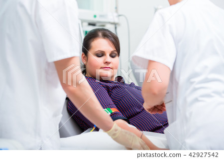 Doctors assistant checking access at female blood giver Doctors assistant checking access at female blood giver 42927542