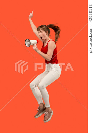 Beautiful young woman jumping with megaphone isolated over red background Beautiful young woman jumping with megaphone isolated over red background 42928118
