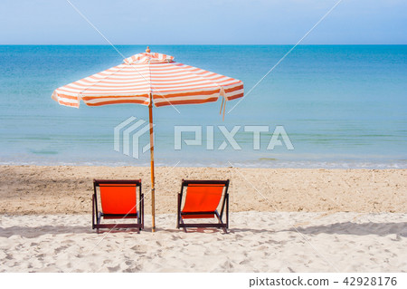 Two red wooden chairs and beach umbrella. Two red wooden chairs and beach umbrella. 42928176