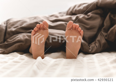 Young boy bare feet in bed under blanket. 42930121