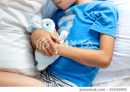Little boy sleeping in bed holding his bunny robbit. 42930985