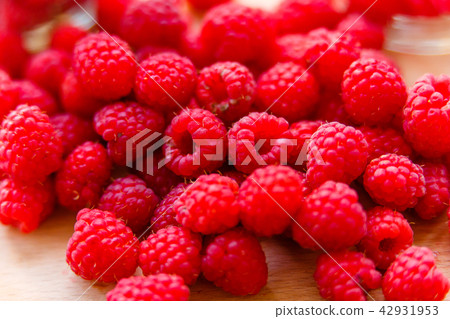 Juicy raspberries lying on wooden cutting board Juicy raspberries lying on wooden cutting board 42931953