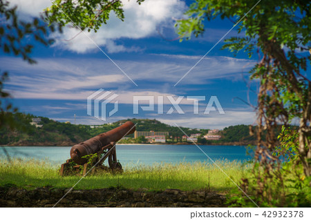 Old cannon in the fort is looking at sea with amazing clouds and island on background Old cannon in the fort is looking at sea with amazing clouds and island on background 42932378