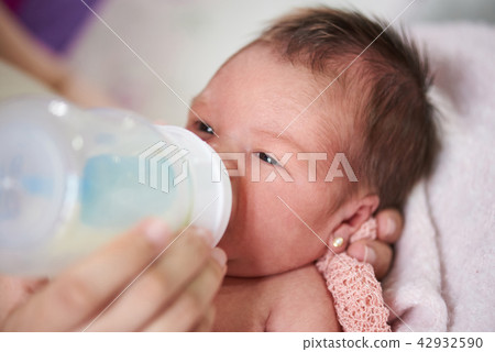 Mom feeding newborn from plastic bottle Mom feeding newborn from plastic bottle 42932590