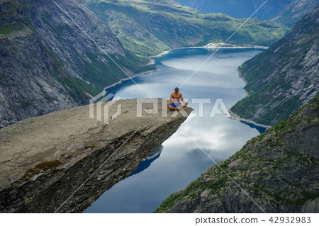 Yog is praying on the edge Trolltunga. Norway 42932983