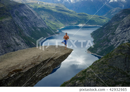 Yog is praying on the edge Trolltunga. Norway 42932985