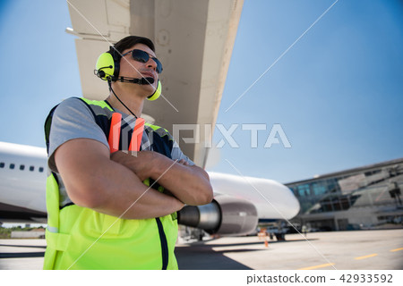 Airport worker in sunglasses and headphones crossing arms Airport worker in sunglasses and headphones crossing arms 42933592