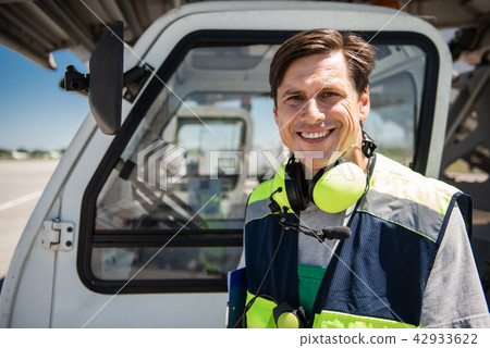 Smiling airport worker posing near vehicle 42933622