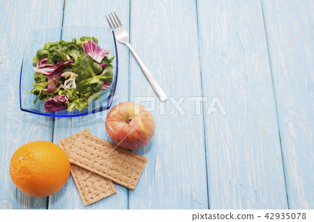 Fresh green leaves of vegetables arugula, salad, on a wooden table. Bright orange and bread Fresh green leaves of vegetables arugula, salad, on a wooden table. Bright orange and bread 42935078