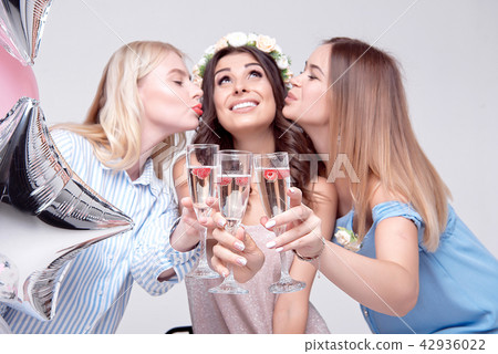 Happy woman is kissed by her friends in both cheeks. Happy woman is kissed by her friends in both cheeks. 42936022