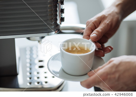 A man with a cup of espresso next to coffee maker A man with a cup of espresso next to coffee maker 42946008