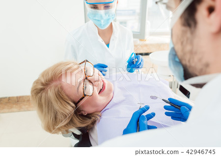 Team of dentists talking to senior patient in their surgery 42946745