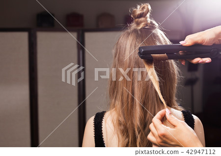 hairdresser curling a hair strand of a model hairdresser curling a hair strand of a model 42947112