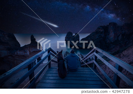 Man with dog looking at Milky Way on the beach Man with dog looking at Milky Way on the beach 42947278
