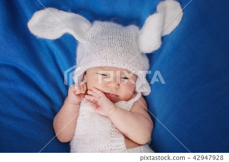 newborn baby in a hat with ears on a blue newborn baby in a hat with ears on a blue 42947928