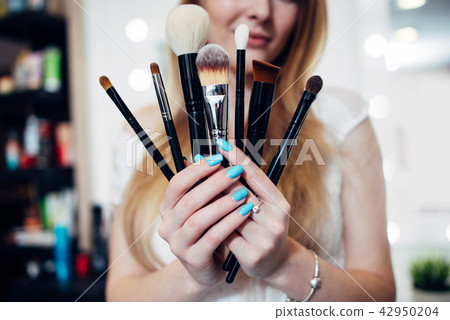 Close-up image of female hands holding a set of make-up brushes Close-up image of female hands holding a set of make-up brushes 42950204