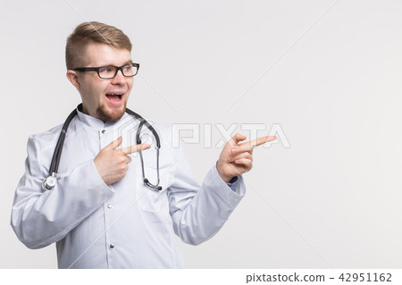 Happy young doctor in studio pointing left Happy young doctor in studio pointing left 42951162