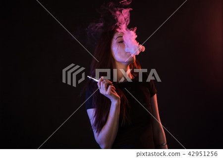 Young woman smoking vape or e-cigarette in neon light Young woman smoking vape or e-cigarette in neon light 42951256