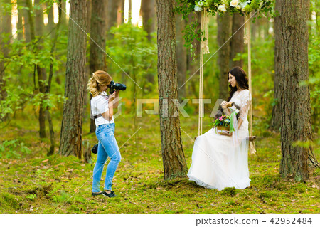 Wedding photographer taking pictures of the bride on a rope swing Wedding photographer taking pictures of the bride on a rope swing 42952484