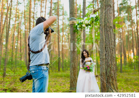 Photographer taking pictures of the bride on a rope swing Photographer taking pictures of the bride on a rope swing 42952581