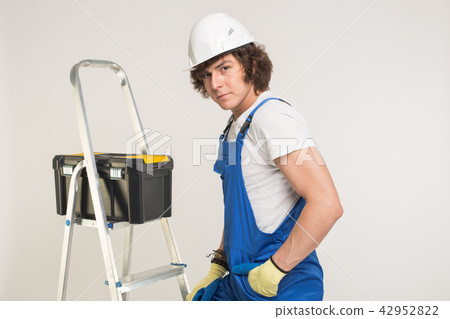 Construction, building and workers concept - Curly haired builder with toolbox and white helmet in 42952822