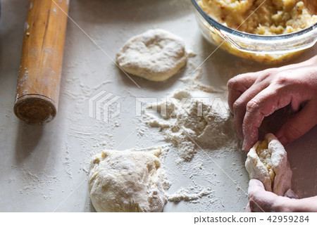 Forming a pie with potatoes by women's hands Forming a pie with potatoes by women's hands 42959284