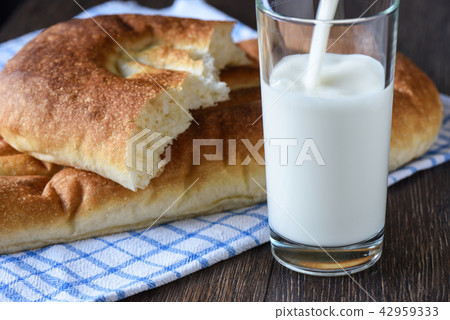 Milk is poured into a glass, bread on a towel 42959333