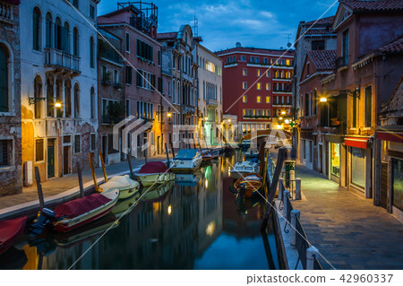 view into a small canal in Venice at night 42960337