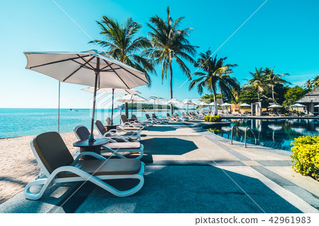 Beautiful tropical beach and sea with umbrella and chair around swimming pool Beautiful tropical beach and sea with umbrella and chair around swimming pool 42961983