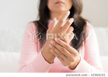 Woman sitting on sofa holds her wrist hand injury Woman sitting on sofa holds her wrist hand injury 42968281