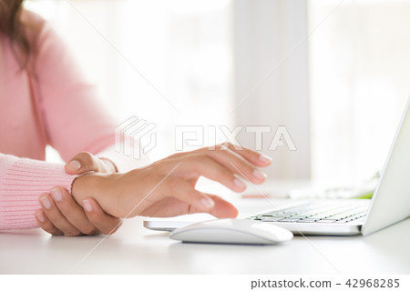 Woman holding her wrist pain from using computer 42968285