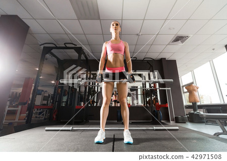 sexy woman squatting with a barbell at the gym sexy woman squatting with a barbell at the gym 42971508