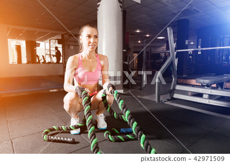 slim girl doing exercises with a cable at the gym 42971509