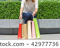 woman sitting and holding colorful shopping 42977736