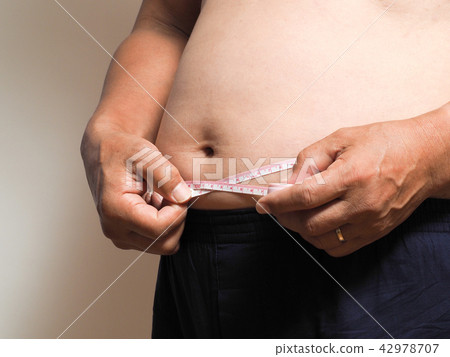 A fat man measuring the waist A fat man measuring the waist 42978707