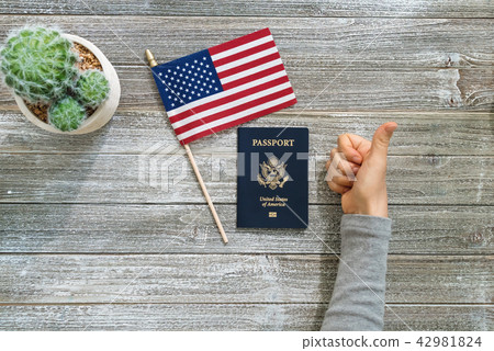 US passport with an American flag on a wooden desk US passport with an American flag on a wooden desk 42981824